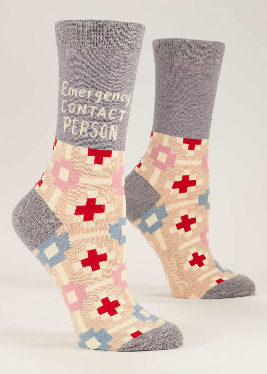 Light gray crew socks for women that say &quot;Emergency Contact Person&quot; on them and feature a repeating geometric cross pattern.