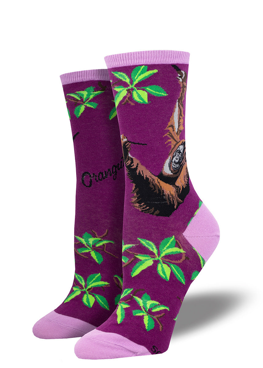 An orangutan climbs in tree branches on these vibrant plum women's crew socks with lighter purple accents.