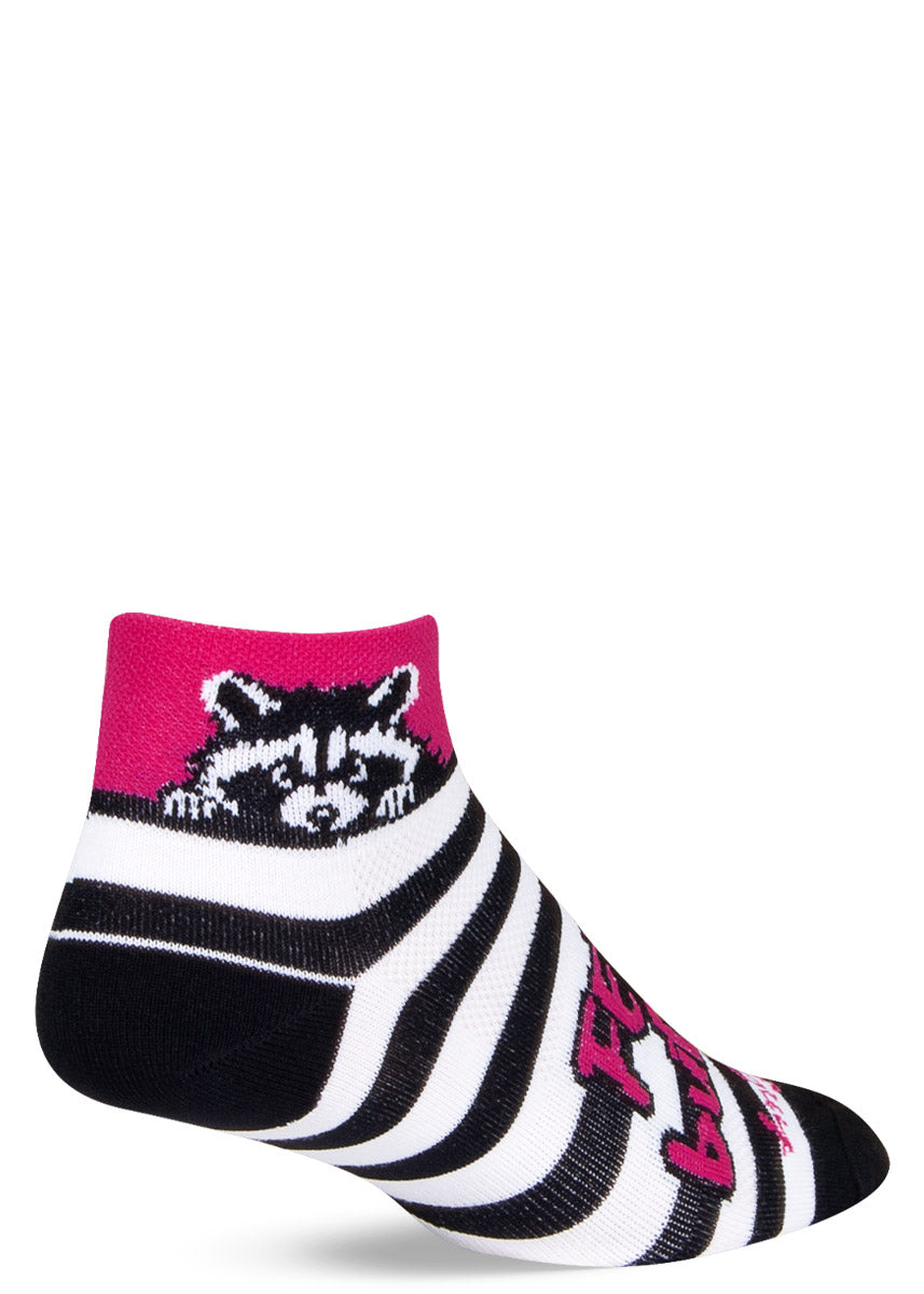 Black- and white-striped ankle sock with hot pink "Feral but Cute" message and raccoon design at cuff.