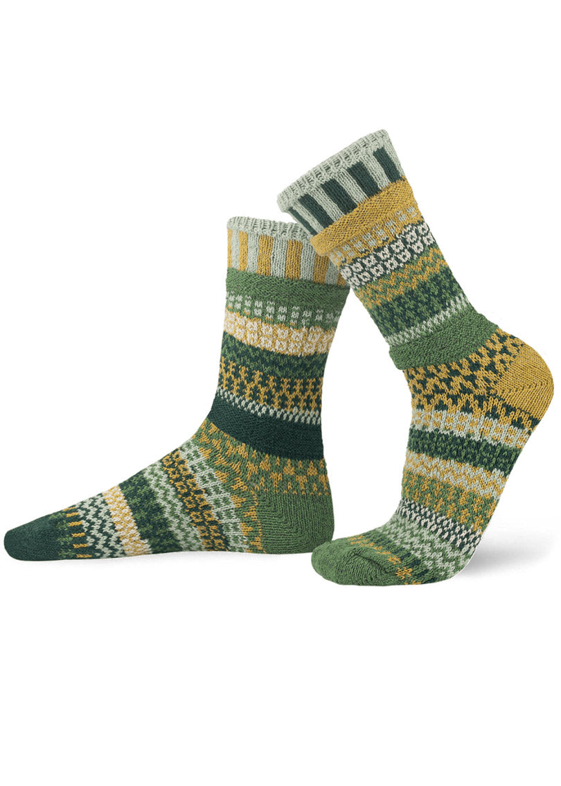 Intentionally mismatched crew socks with different sections featuring various geometric patterns like stripes and dots in shades of green gold, and gray.