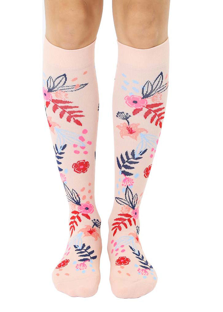 Light pink knee-high compression socks with an allover pattern of red, pink, navy, and light blue floral motifs.