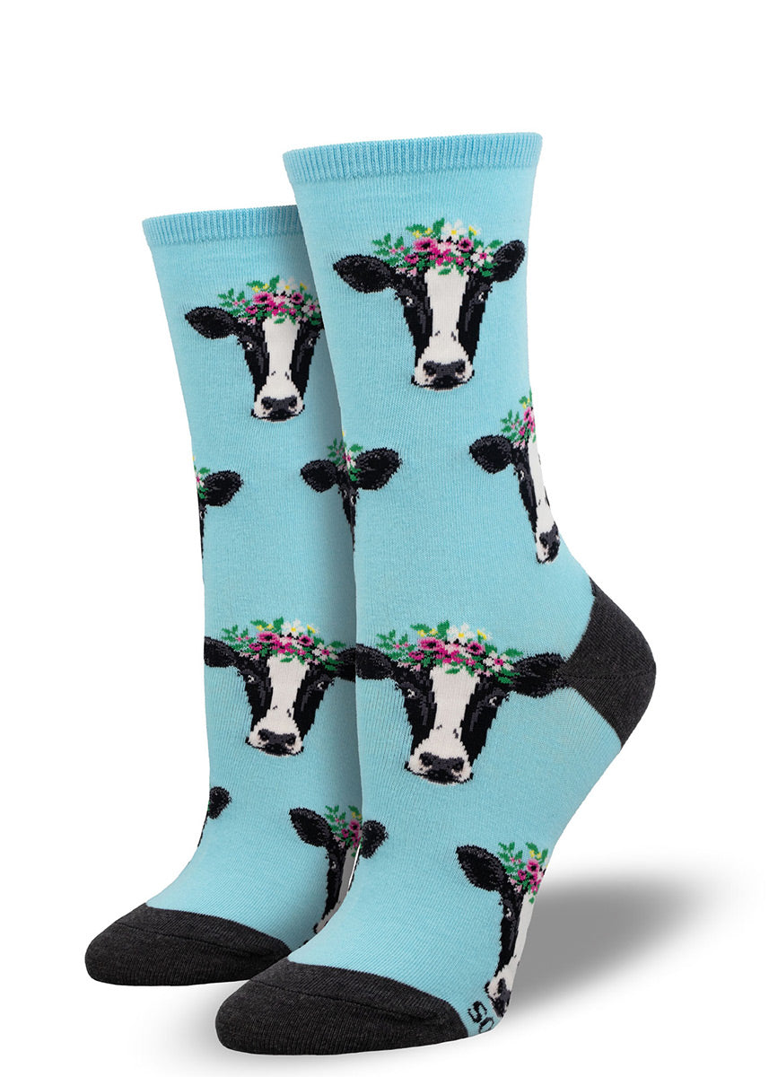 Blue crew socks for women with a repeating pattern of black and white cow faces wearing pink flower crowns.