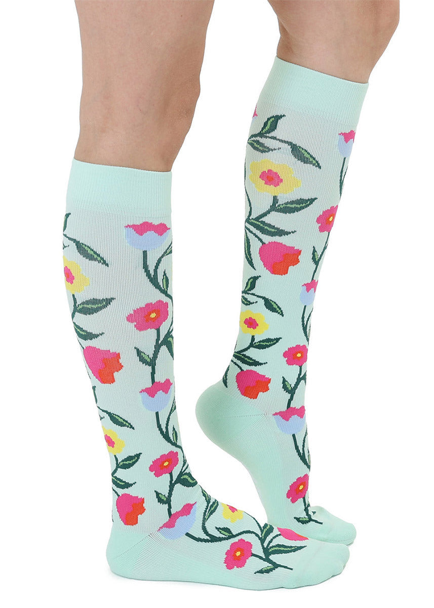 Knee-high socks with colorful floral pattern on a light blue background.