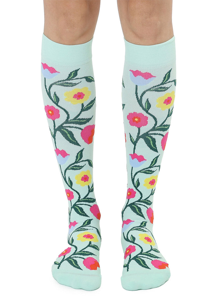 Knee-high socks with colorful floral pattern on a light blue background.