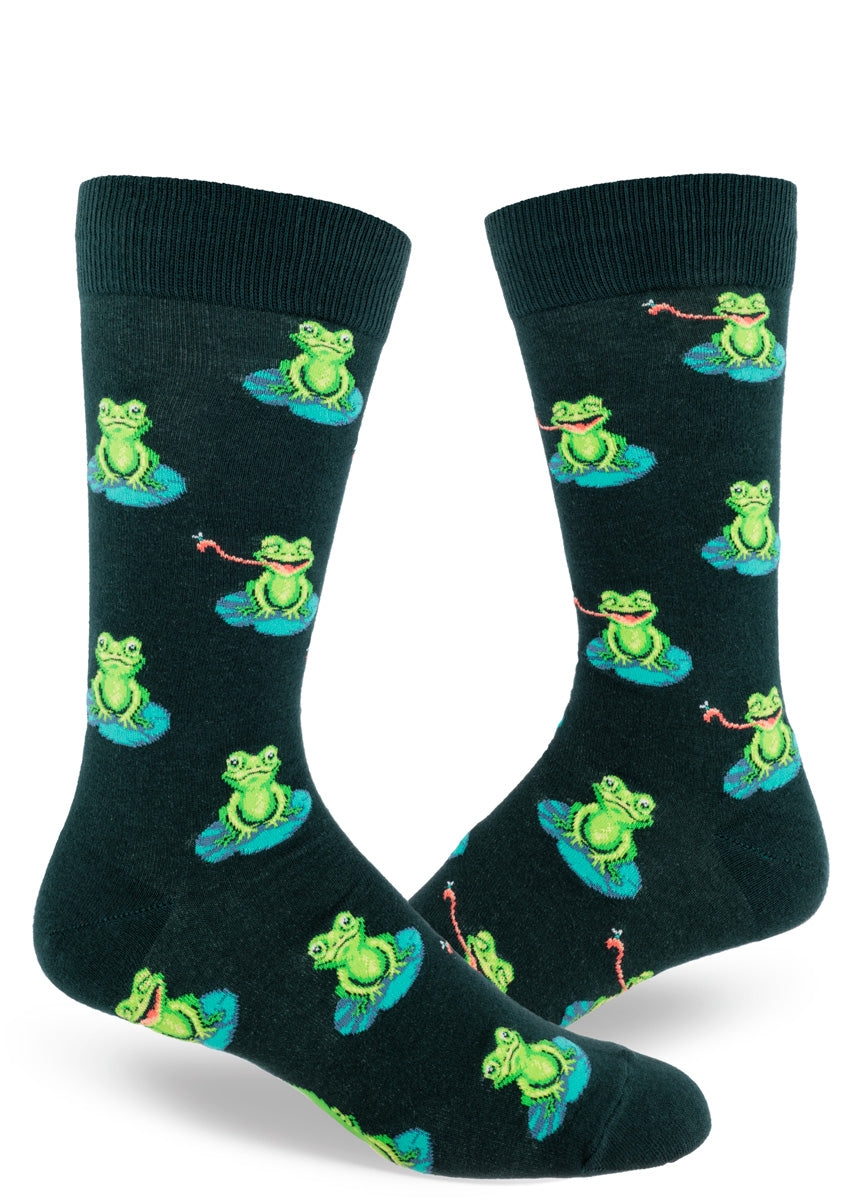 Dark green novelty socks for men show an allover pattern of green frogs sitting on lily pads with some sticking their tongue out to catch a fly.