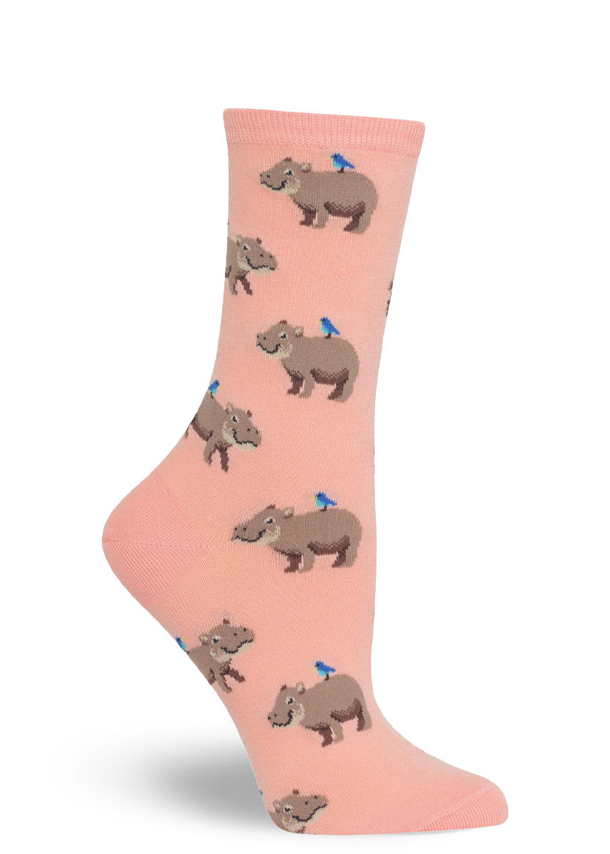 Pink crew socks for women with an allover pattern of hippos with a blue bird resting on their backs.