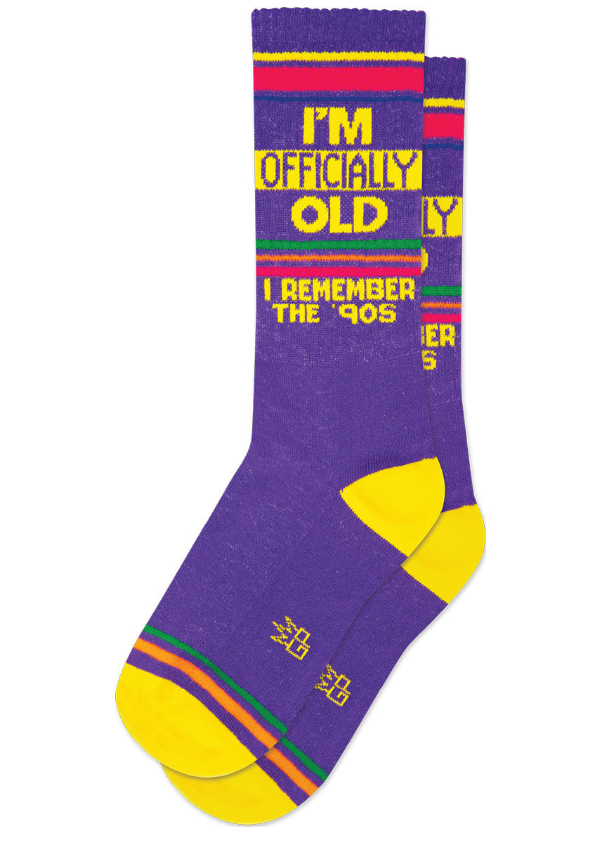 Purple retro-style striped gym socks say “I&#39;M OFFICIALLY OLD, I REMEMBER THE &#39;90S&quot; accented with yellow and rainbow stripes at the heel and toe.