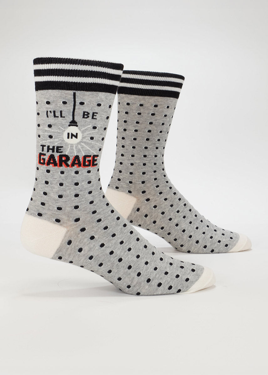 Gray men's crew socks with black polka dots and text that says, "I'll be in the garage."