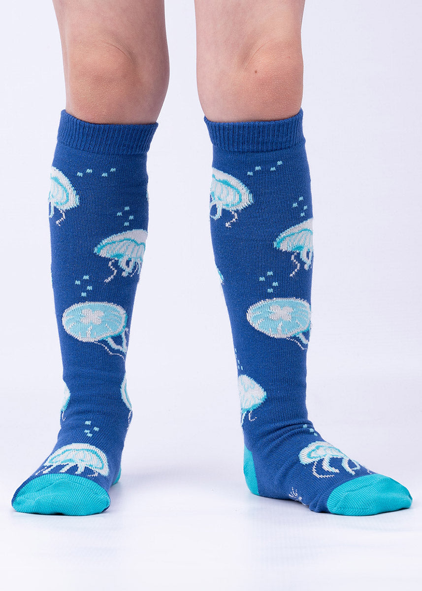 Kids&#39; knee-high socks with glow-in-the-dark jellyfish on a royal blue background.