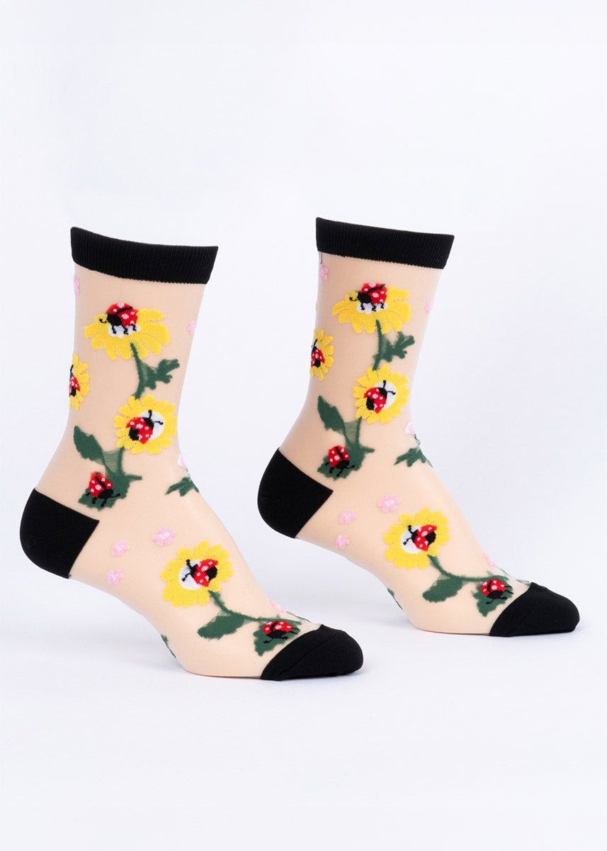 Pair of women's crew socks with ladybug and floral design on a sheer background with black accents.
