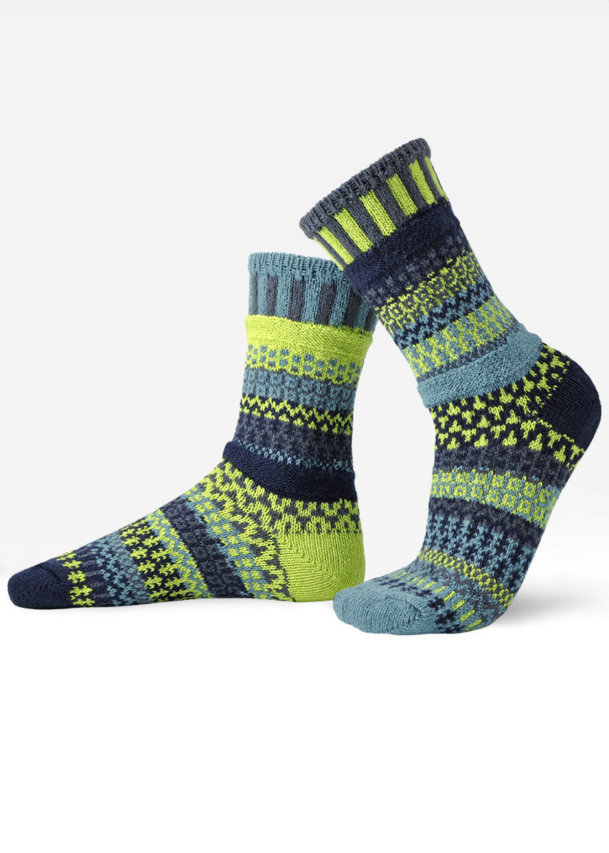 Intentionally mismatched crew socks with different sections featuring various geometric patterns like stripes and dots in shades of blue, lime green and dark gray.