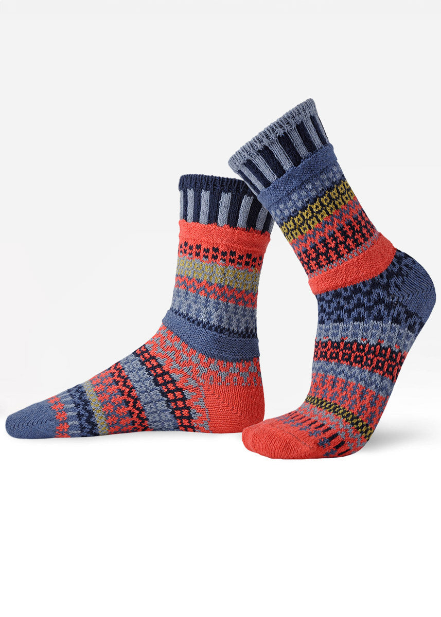 Intentionally mismatched crew socks with different sections featuring various geometric patterns like stripes and dots in shades of blue, coral and moss green.