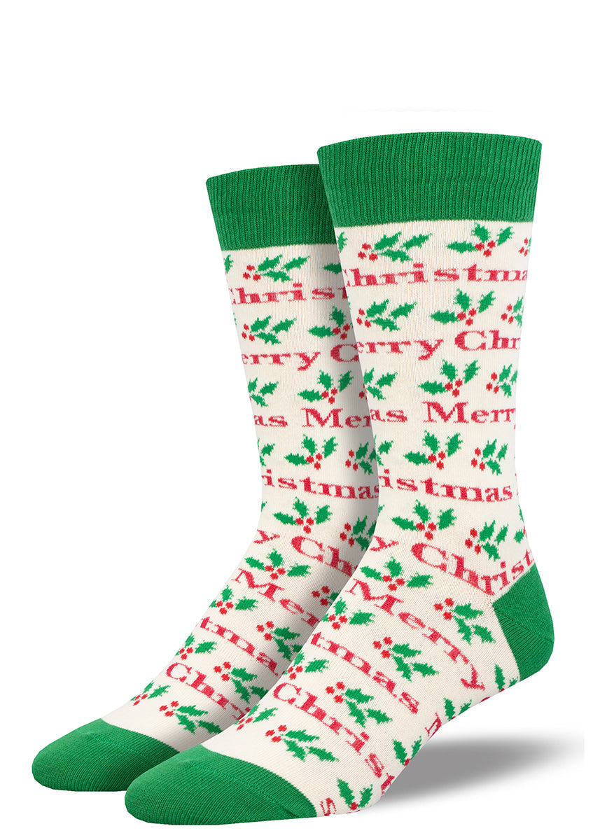 White novelty holiday socks for men with a dark green cuff, toe, and heel featuring an allover pattern of holly leaves and the words "Merry Christmas" in a red font.