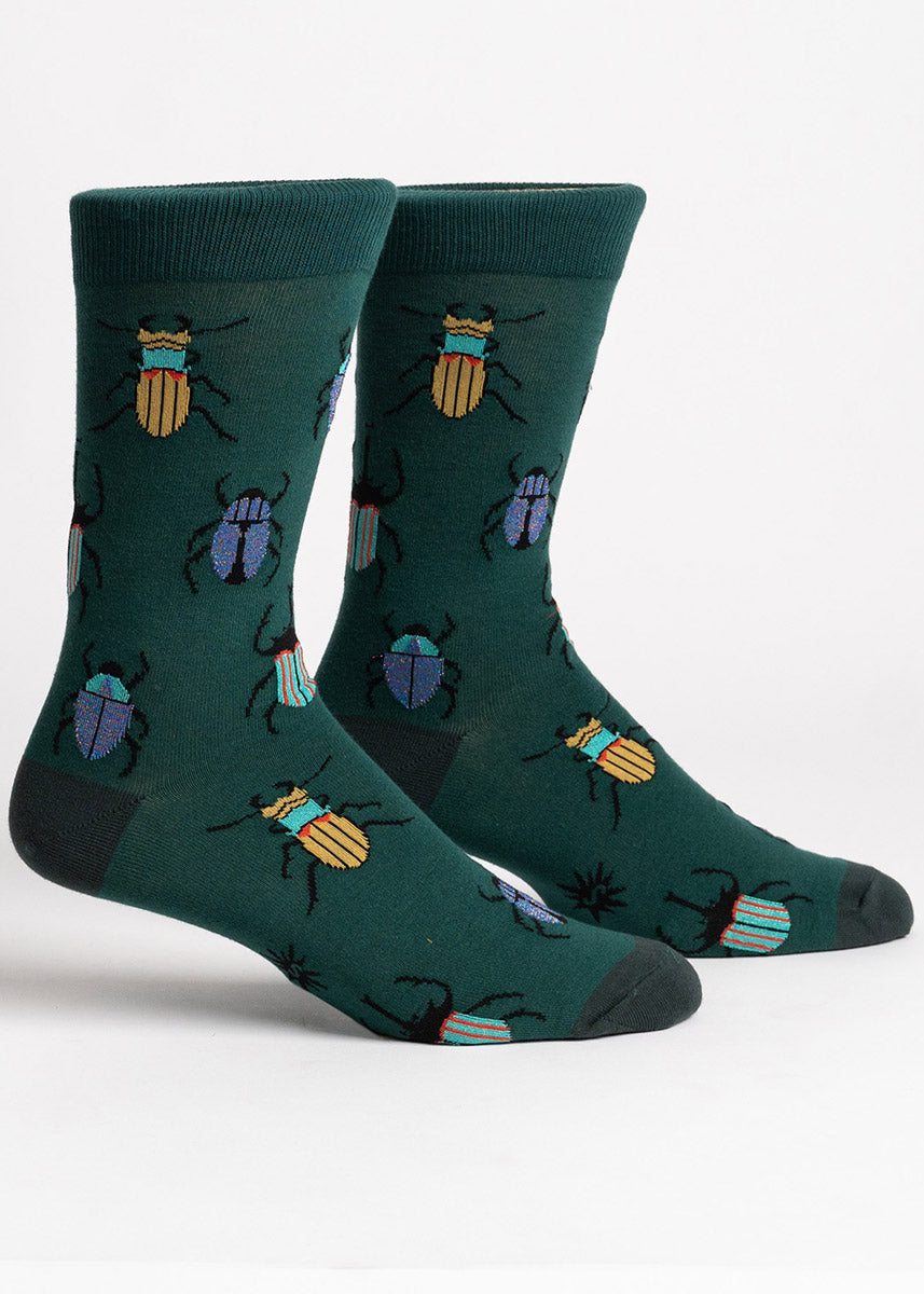 Dark green crew socks for men featuring a repeating pattern of yellow, teal, blue, and orange beetles with some blue and rainbow shimmer elements.