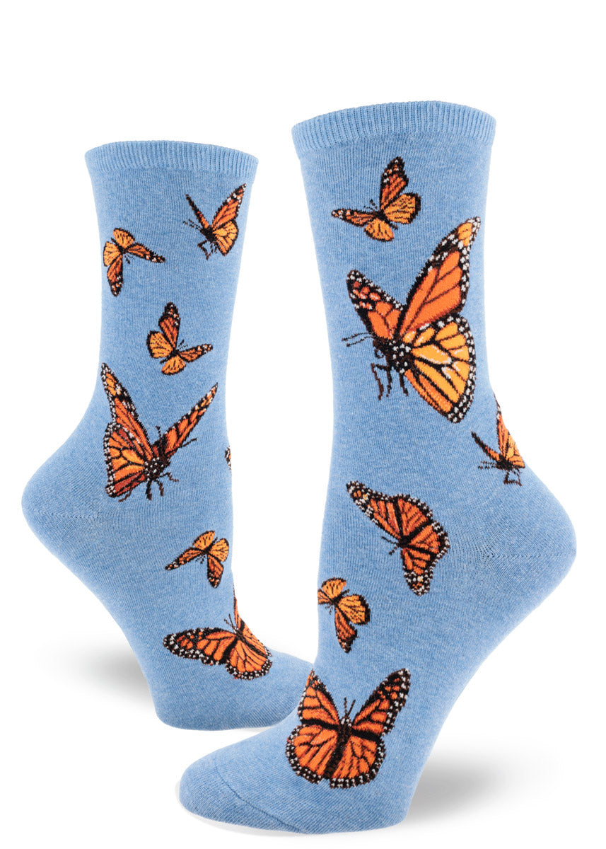 Blue crew socks for women with an allover pattern of orange monarch butterflies in various poses in flight.