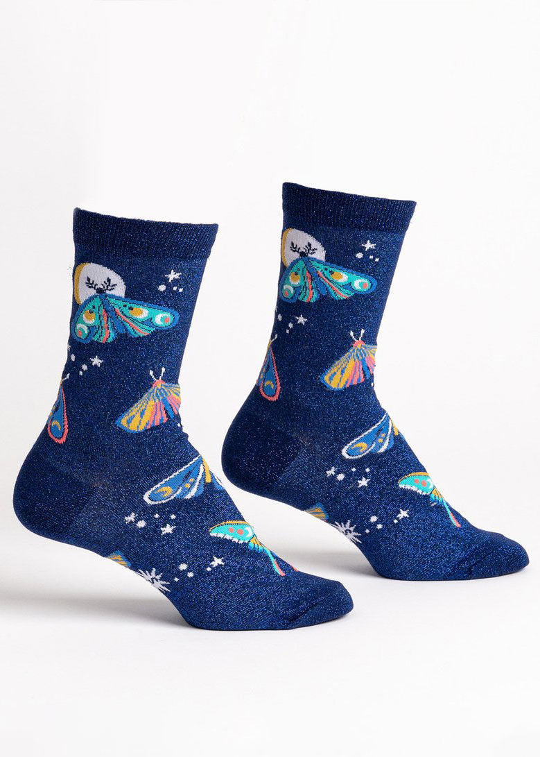 Dark blue shimmer crew socks for women with a design of colorful patterned moths, a big white moon, and stars against a sparkly blue background. 