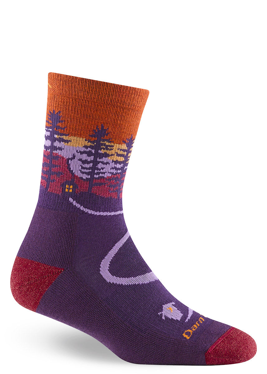 Red, orange and purple wool crew socks for women feature an image of a countryside sunset complete with a cabin surrounded by trees and animals.