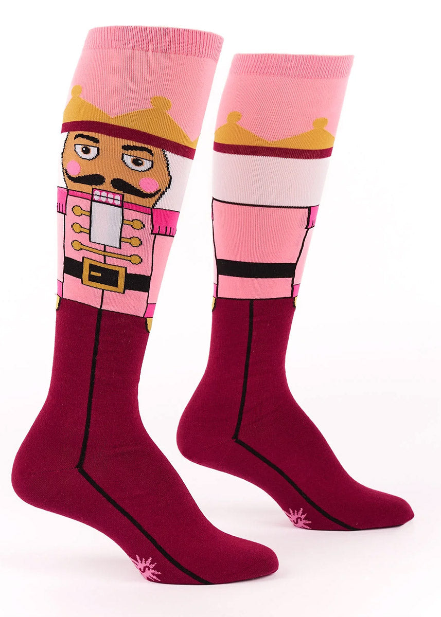Pink knee socks for women featuring a nutcracker in a pink uniform and gold crown up the leg.