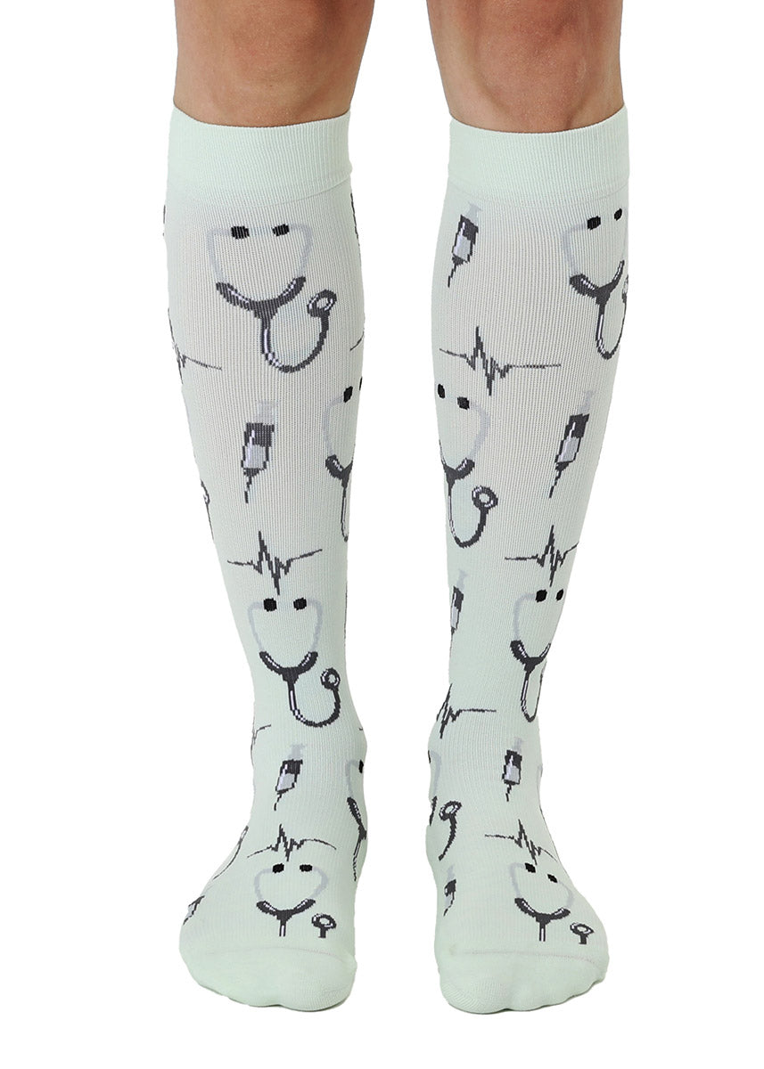 Pale mint green knee-high compression socks with an allover pattern in a medical theme including stethoscopes, syringes and more. 