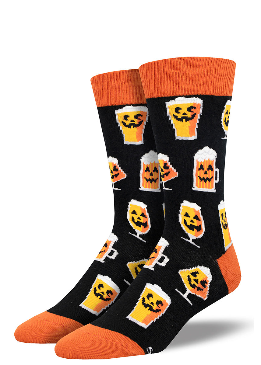 Black crew socks for men with orange accents and an allover pattern of glasses of pumpkin beer with smiling jack-o-lantern faces.