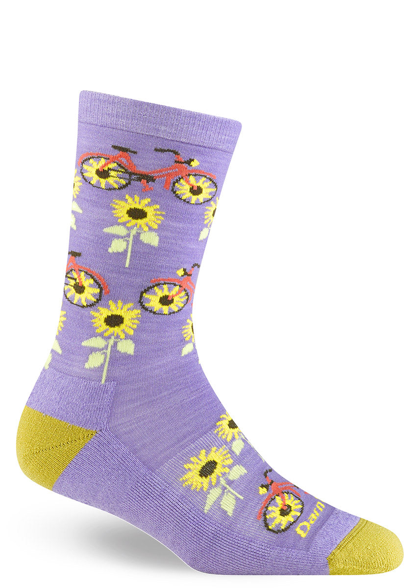 Purple women&#39;s wool crew socks with a design that puts sunflowers in the middle of red bicycles&#39; wheels with more flowers growing in between them.
