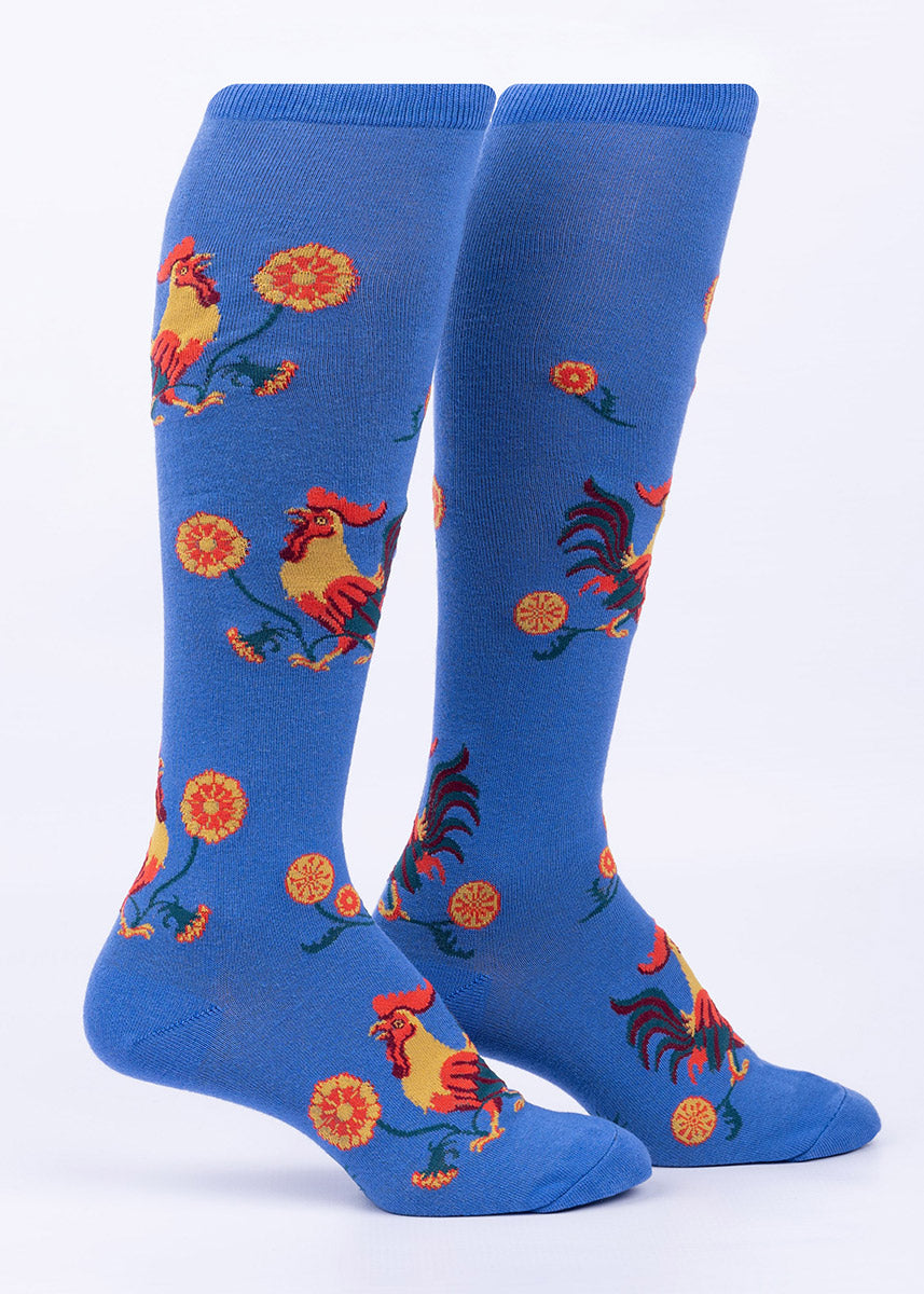 Violet blue knee socks with a pattern of roosters strutting among red and yellow flowers.