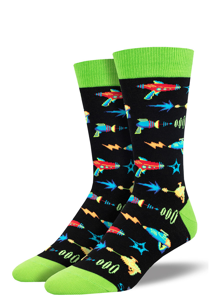 Black novelty crew socks for men with a lime green cuff, heel, and toe and an allover pattern of sci-fi style ray gun blasters in various bright colors. 