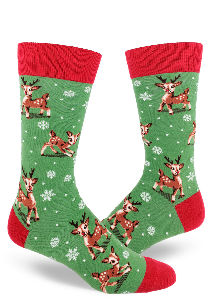 Green holiday novelty socks for men with a red cuff, heel, and toe and an allover pattern of Christmas reindeer and snowflakes.