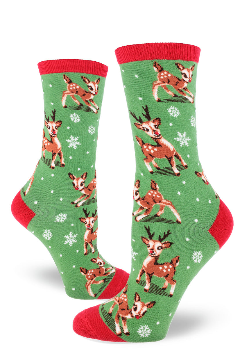 Green holiday novelty socks for women with a red cuff, heel, and toe and an allover pattern of Christmas reindeer and snowflakes.