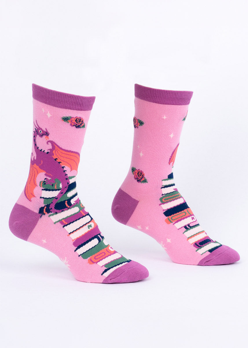Pink women's crew socks featuring purple dragons perched on stacks of colorful books.