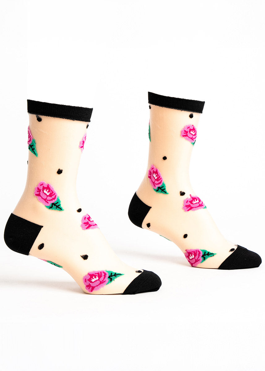 Sheer crew socks with a black cuff, heel and toe for women and an allover pattern of black polka dots and pink roses. 