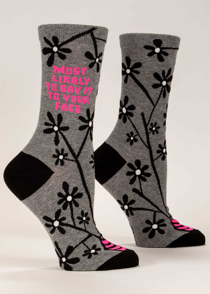 Gray women&#39;s crew socks with a black floral design and the words “Most Likely to Say It to Your Face&quot; in hot pink.