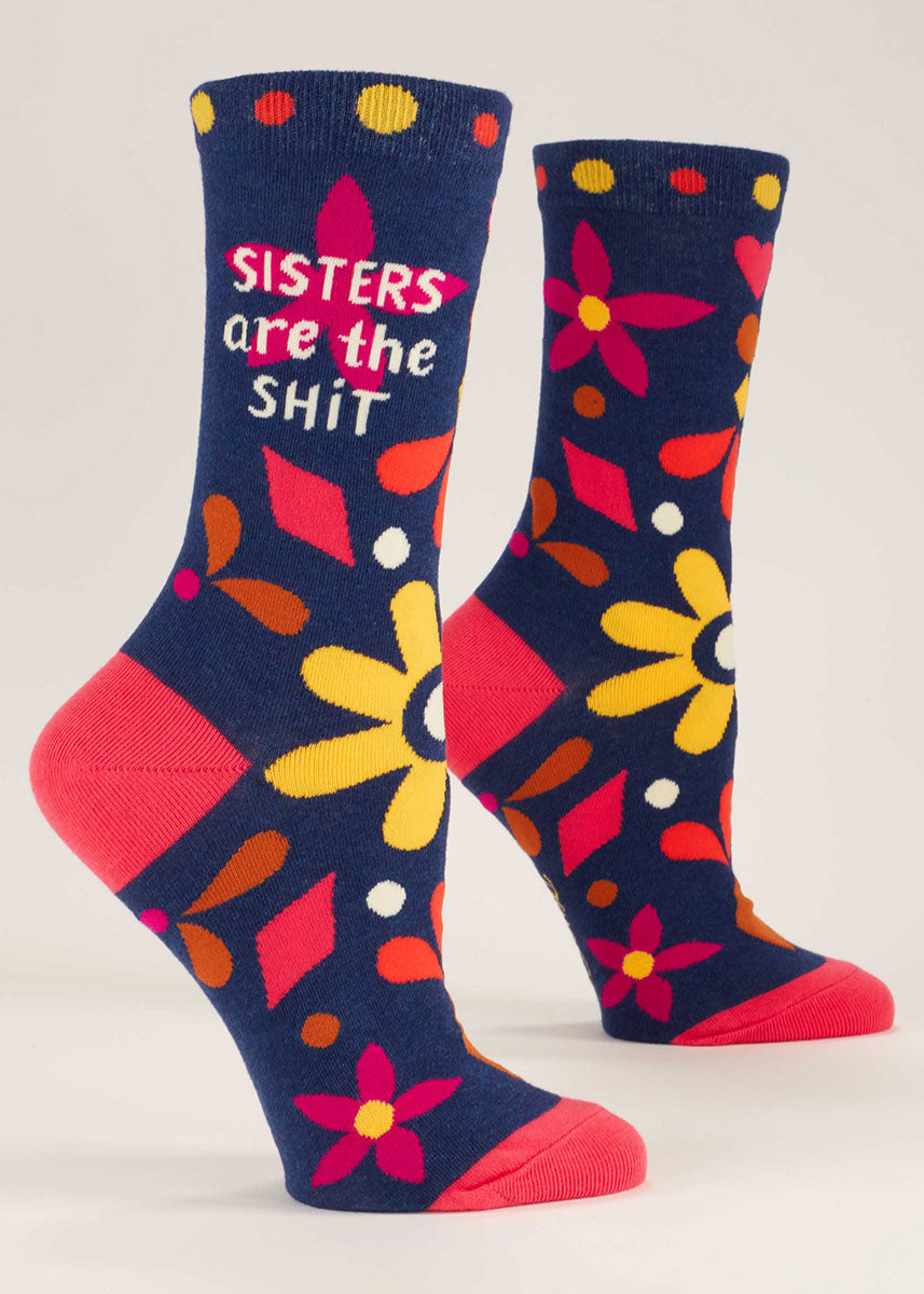 Dark blue crew socks for women that say &quot;Sisters Are the Shit&quot; on them and have a colorful floral design.