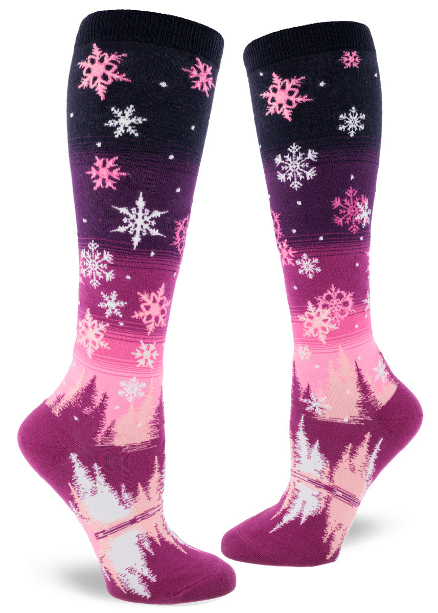 Pink snowflake knee-high socks for women with a landscape of a snowy night sky and pink fir trees.