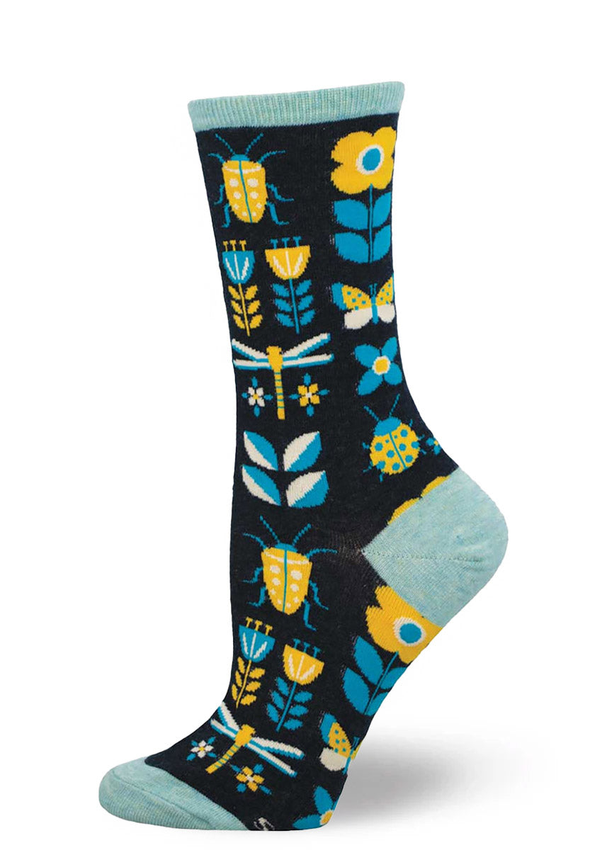 Navy crew socks for women with an allover pattern of flowers and bugs in yellow, blue, and white. 