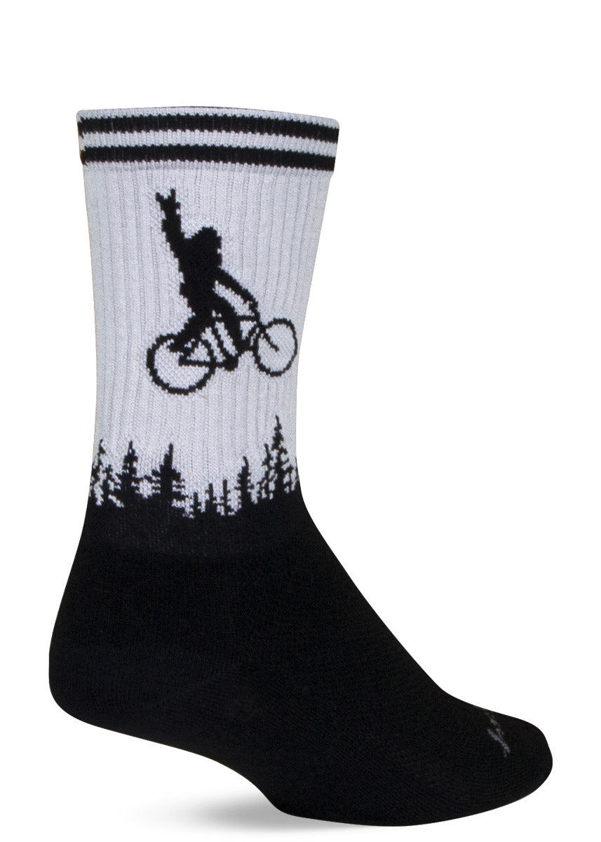 Gray and black ribbed athletic crew socks with the silhouetted image of Sasquatch flying through the sky on a bike over a forest while hand-gesturing "rock on."