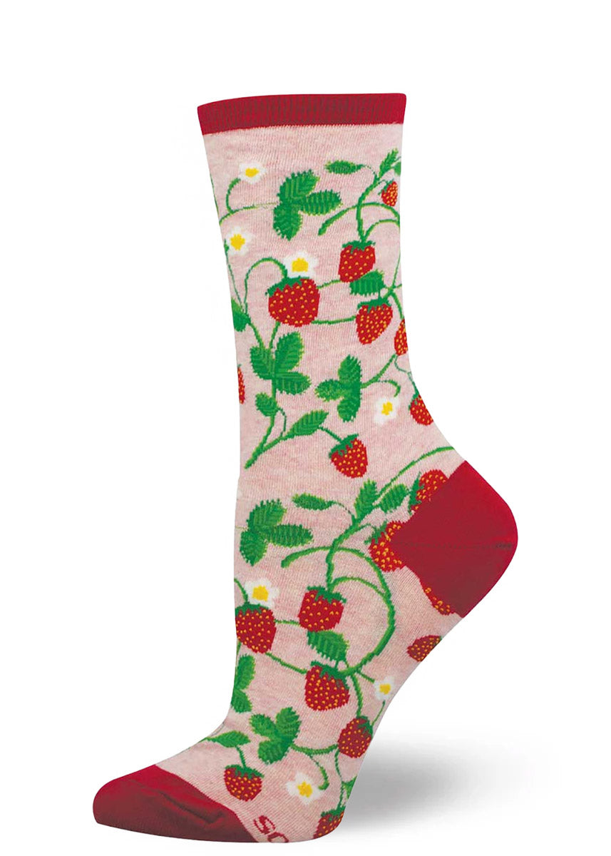 Pink crew socks for women with an allover pattern of green vines, red strawberries, and white flowers.