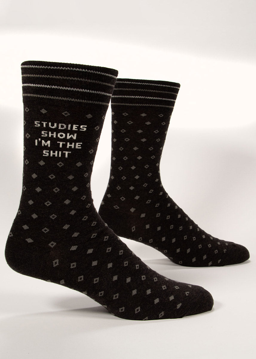 Charcoal gray men&#39;s dress socks with a subtle diamond pattern and “Studies Show I&#39;m the Shit” knit into the leg. 