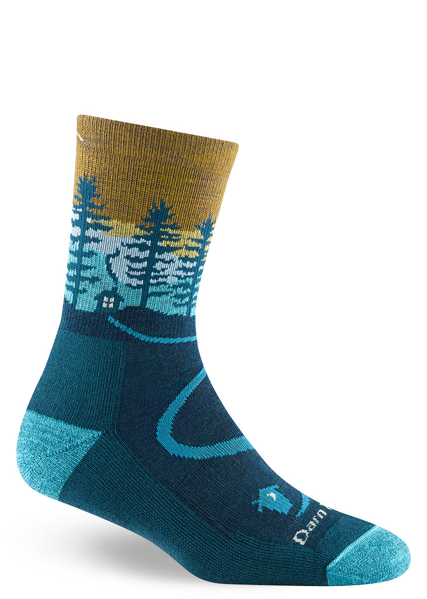 Gold, teal and aqua wool crew socks for women feature an image of a countryside sunset complete with a cabin surrounded by trees and animals.