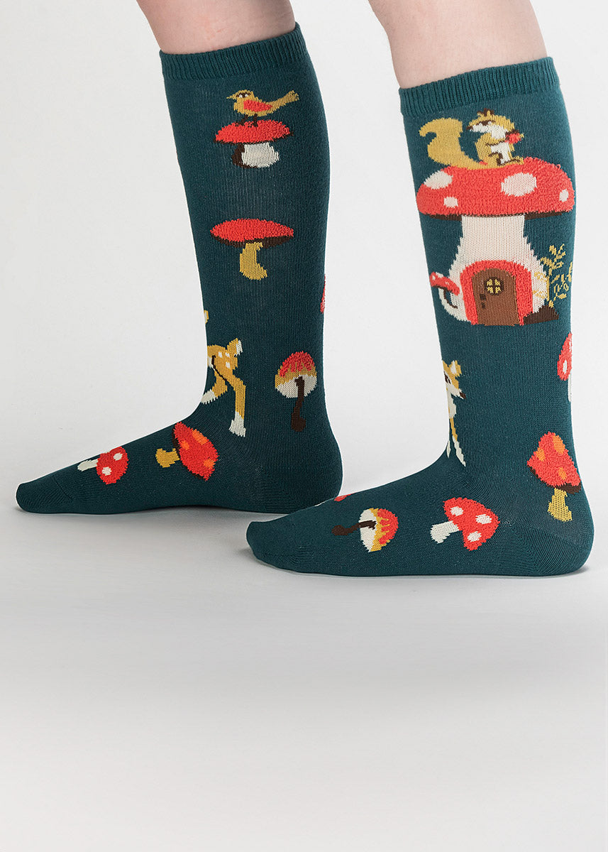 Dark teal knee socks for kids show squirrels, deer and birds atop and around red toadstools that are fuzzy to the touch.