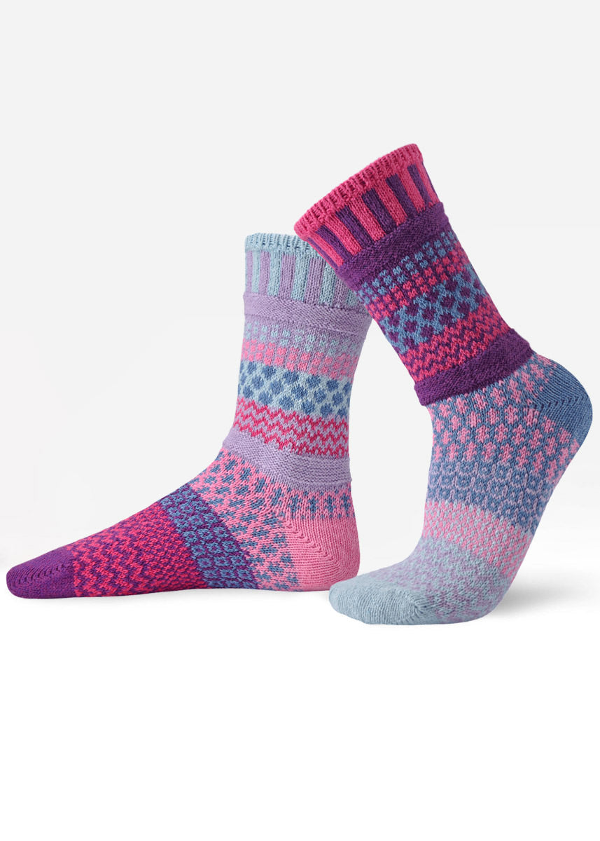 Intentionally mismatched crew socks with different sections featuring various geometric patterns like stripes and dots in shades of blue, aqua, purple and pink.