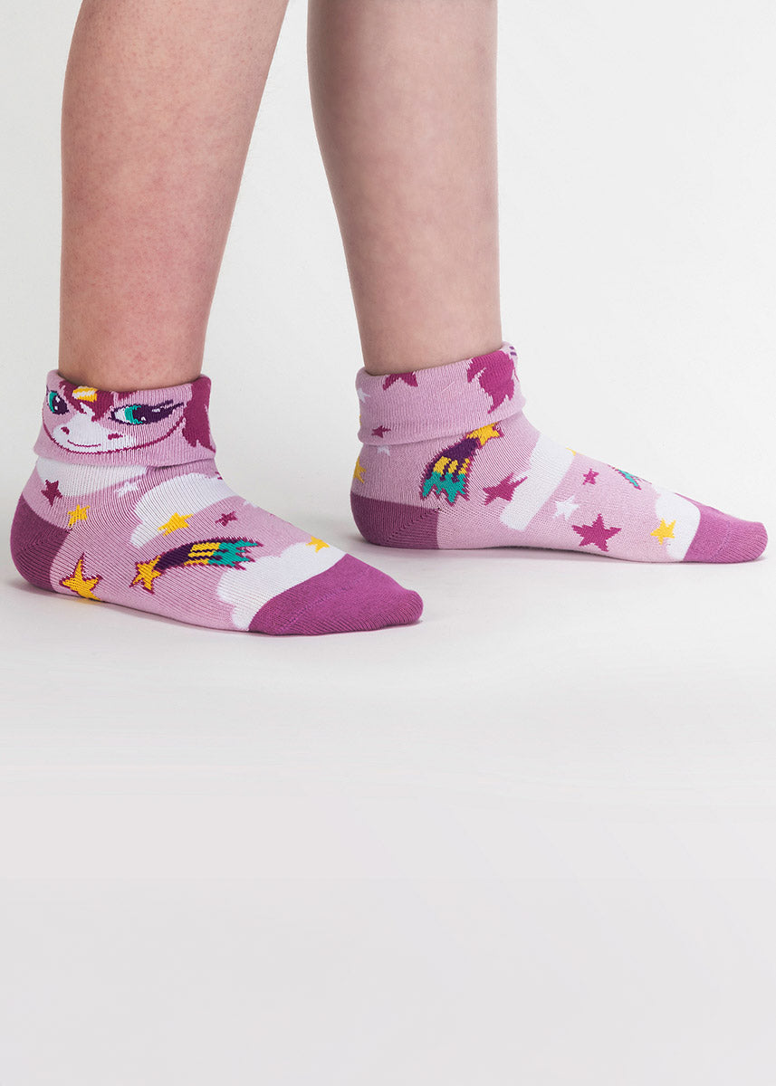 Cuffed kids&#39; socks in light purple-pink with shooting stars, clouds and a unicorn face on the turned-down cuff that flips up to say “99% unicorn.” 