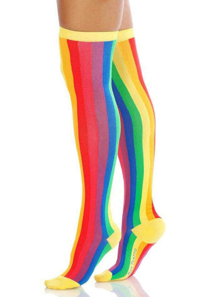 A model poses against a white background wearing vertical rainbow striped over-the-knee socks.