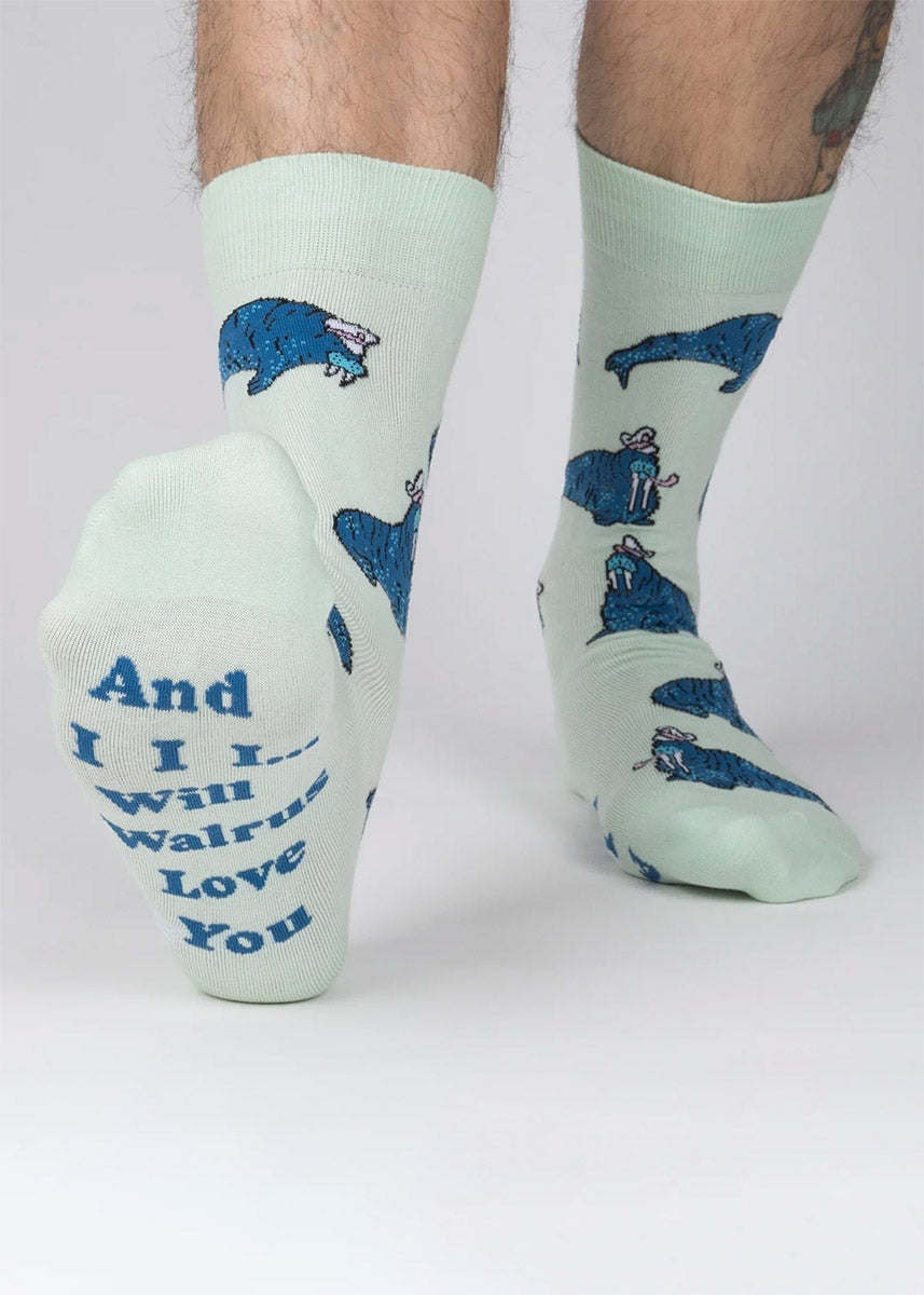 Pale green crew socks for men with an allover pattern of blue walruses wearing ship captain hats and smoking pipes. 