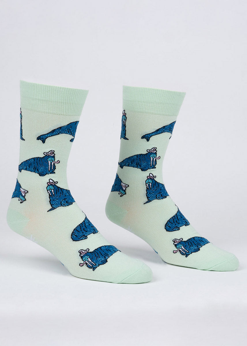 Pale green crew socks for men with an allover pattern of blue walruses wearing ship captain hats and smoking pipes. 