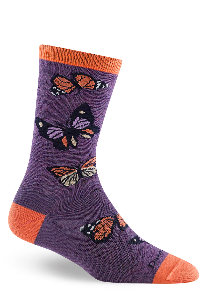 Purple wool crew socks for women that have an allover pattern of monarchs and other kinds of butterflies in shades of orange and yellow.