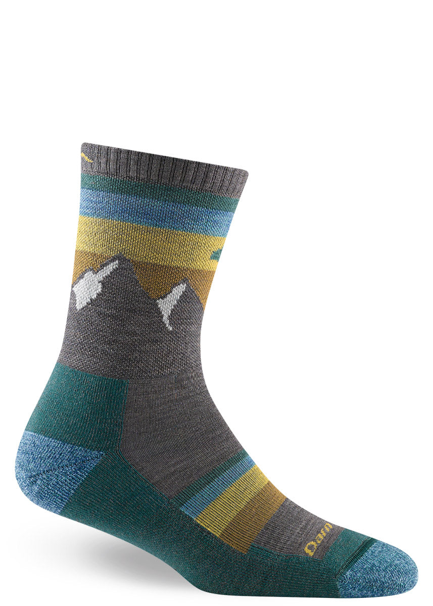 Gray hiking socks for women with snow-capped mountain peaks and a background of teal, blue, and yellow stripes.