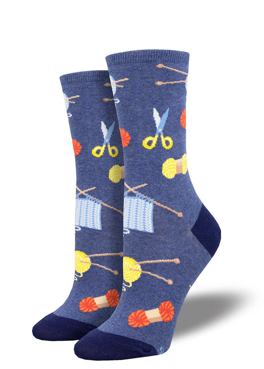 Dark blue novelty crew socks for women featuring an allover pattern of various knitting supplies such as balls of yarn, knitting needles, and more.
