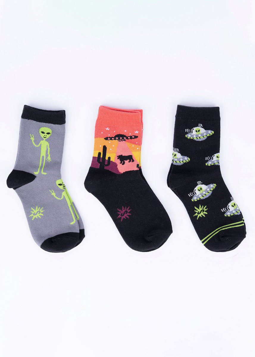 Three pairs of coordinating gray and black socks for kids with colorful accents in an alien abduction theme.