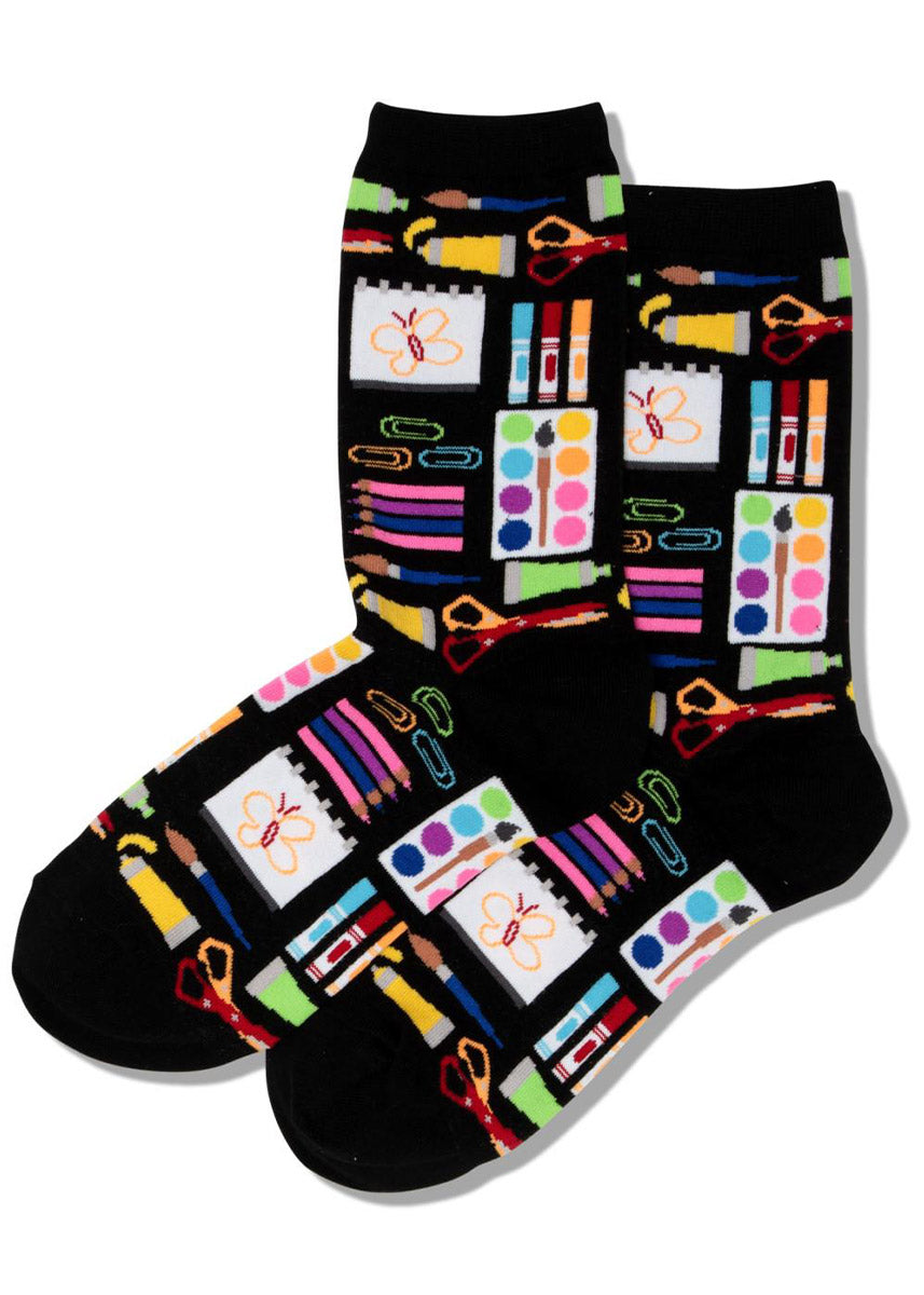 Black crew socks for women with colorful scissors, watercolor paints, markers, colored pencils and other art supplies.
